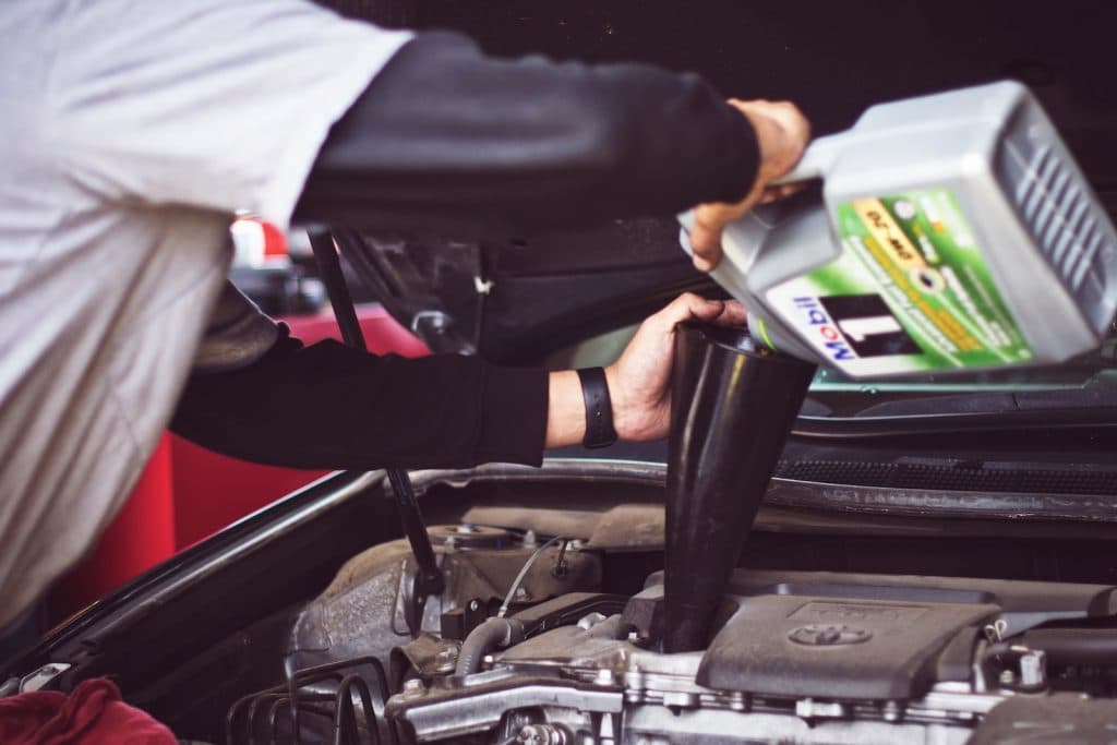 Technician pouring fresh oil into a German car engine